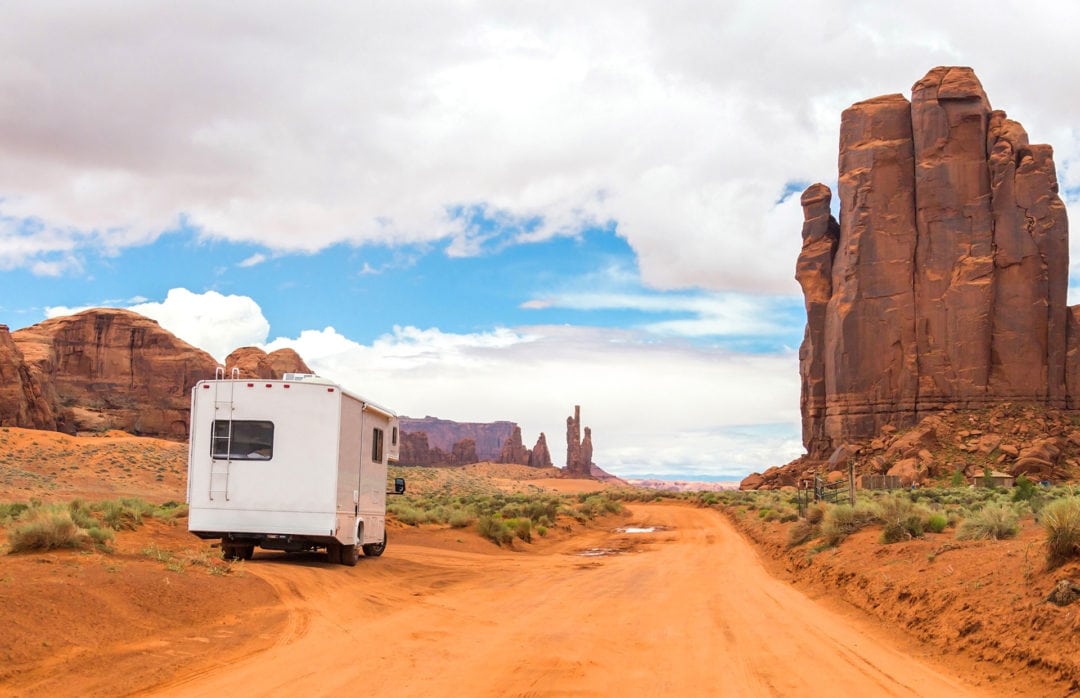 RV surrounded by red cliffs in Monument Valley